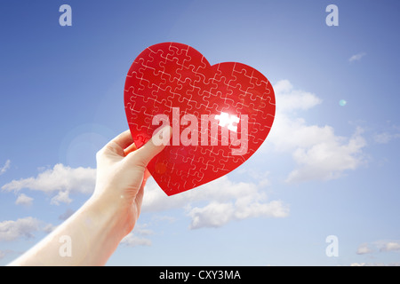 Hand holding a red heart shape against the sun Stock Photo