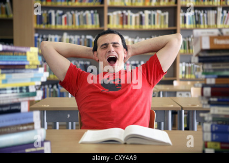 Student yawning and being lazy in a university library Stock Photo