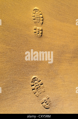 Footprints on a sandy beach with boot marks clearly visible in the sand Stock Photo