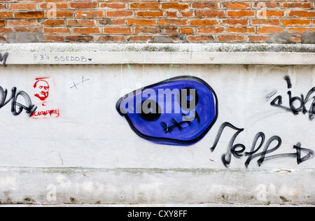 Graffiti on a wall in Venice including a striking blue ghost or skull, and a stencilled cantastorie Stock Photo