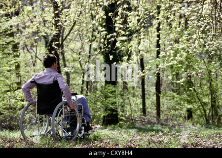 Man sitting in wheelchair in woods Stock Photo
