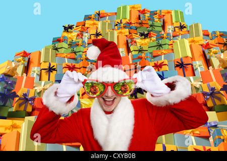 Santa Claus wearing oversized glasses, standing in front of a pile of gifts Stock Photo