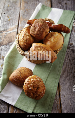 Various types of bread in a basket lying on a rustic table Stock Photo