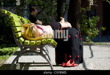Woman lying on a green park bench, relaxing, Berlin Stock Photo