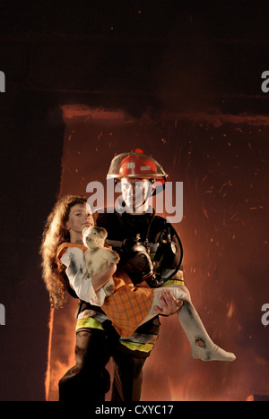 Firefighter rescuing a girl from a burning building Stock Photo