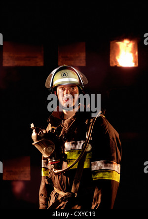 Firefighter in front of a burning building Stock Photo