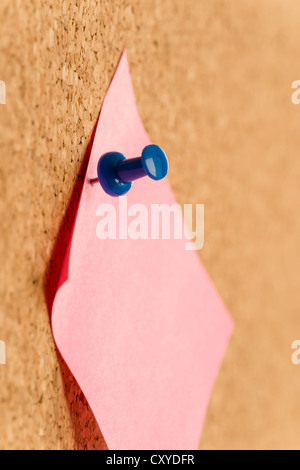 Post-it pink sticker note with pin on board close-up Stock Photo