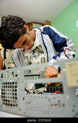 Teenager, 18 years old, a former hired killer and member of a gang of youths, Mara, learning how to build a working computer Stock Photo