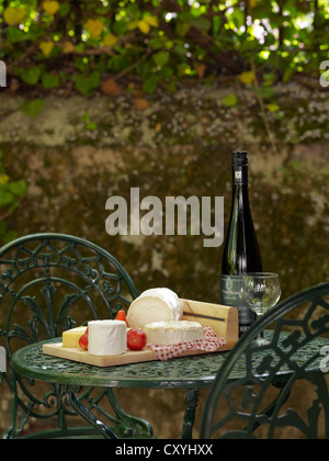 Still life, cheese buffet and wine on a cast-iron garden table in a backyard Stock Photo