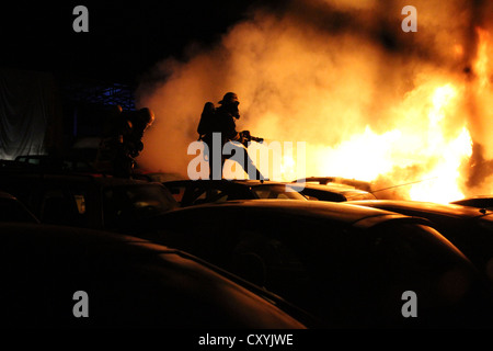 Arson attach on cars, firefighters trying to extinguish burning cars in the car park of a car dealer in Berlin-Schmoeckwitz Stock Photo