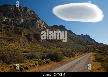 Dirt road to Cochrane in the evening light under a big white cumulus cloud, Altocumulus lenticularis, Rio Chacabuco, Cochrane Stock Photo