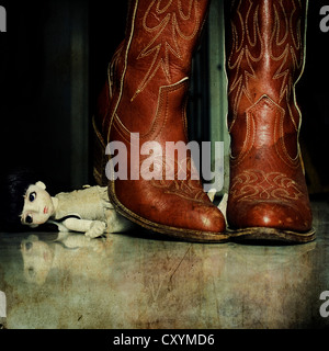 a pair of cowgirl boots over a little doll Stock Photo
