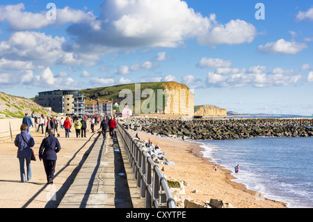 People walking along West Bay, Dorset, promenade on the Dorset coast, UK Stock Photo