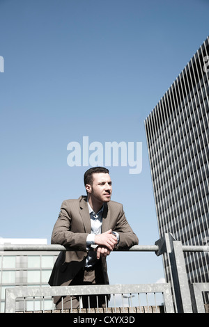 Young business man standing pensively against a railing Stock Photo