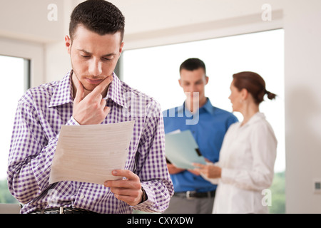 Young man working with documents in front of colleagues Stock Photo