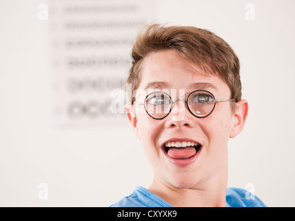 Teenage boy, portrait wearing thick-glassed glasses in front of a sight test Stock Photo