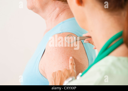 Dermatologist examining a patient with a magnifying glass Stock Photo