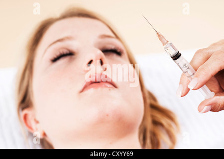 Syringe in front of the face of a patient, Botox treatment Stock Photo