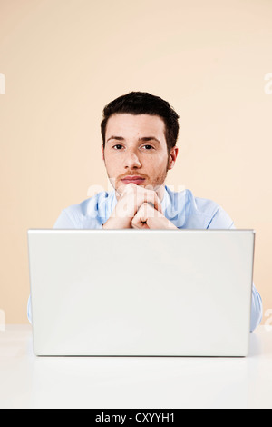 Young man sitting in front of his laptop computer, thoughtful Stock Photo
