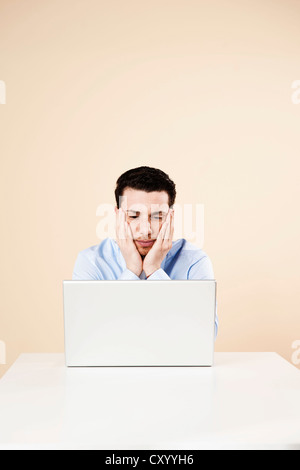 Young man sitting in front of his laptop computer, thoughtful Stock Photo