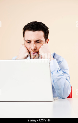 Young man sitting in front of his laptop computer, thoughtful Stock Photo