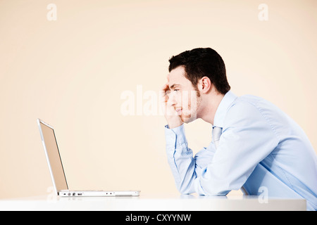 Young manager sitting pensively at his notebook Stock Photo