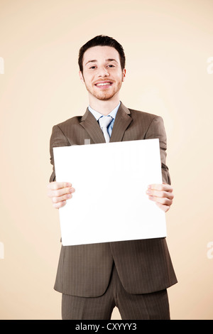 Young man wearing a suit holding a blank board in his hands Stock Photo