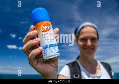 Young woman holding a can of insect repellent in her hand, New Zealand, Oceania Stock Photo