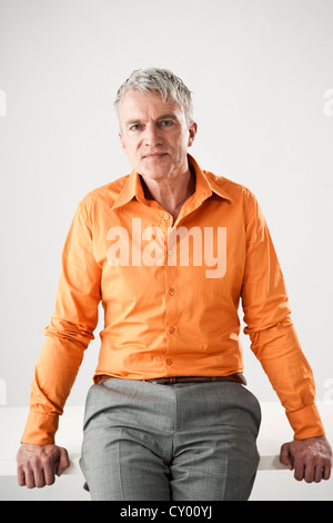 Businessman casually sitting on a desk Stock Photo