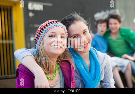 Teenagers sitting in front of a wall with graffiti Stock Photo