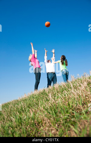 Girl playing ball with her grandparents on a meadow Stock Photo