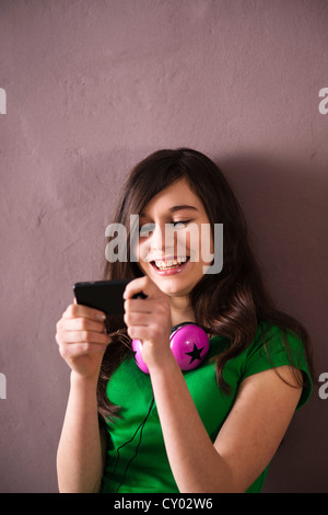 Girl wearing headphones and using a cell phone Stock Photo