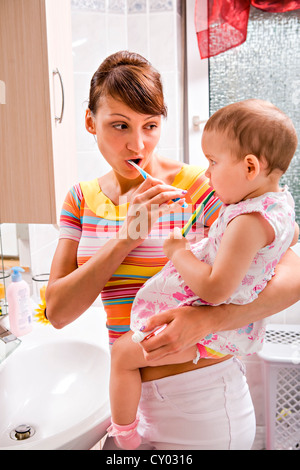 Mother and daughter brushing teeth together, bathroom Stock Photo