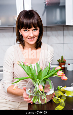 Young woman with a bunch of tulips in the kitchen Stock Photo