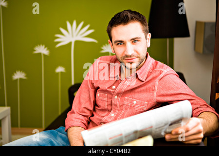 Young man at home, reading a newspaper Stock Photo