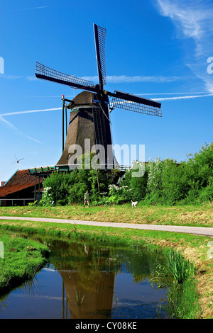 Netherlands, North Holland, Zaanstad, Zaanse Schans, Windmills, Pathway along the canal. Stock Photo