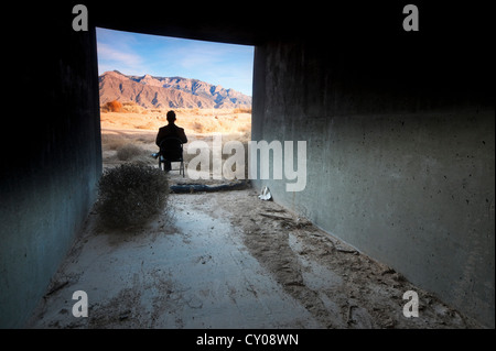 Silhouette of male figure sitting in tunnel in desert Stock Photo