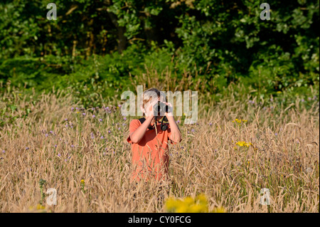 Young boy bird watching in meadow Norfolk summer Model released Stock Photo