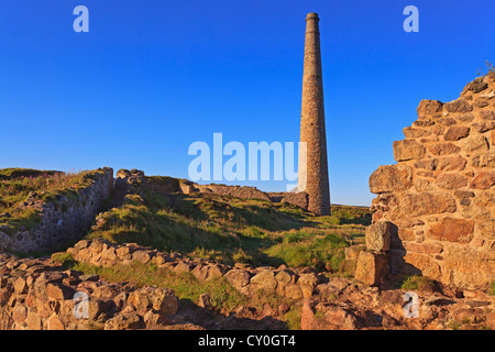 Sunrise at Botallack tin mines in Cornwall, the rising sun has lit up the ruins of the buildings against the clear blue sky. Stock Photo