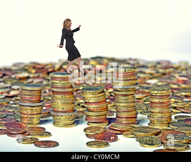 businesswoman walk on euro coin piles Stock Photo