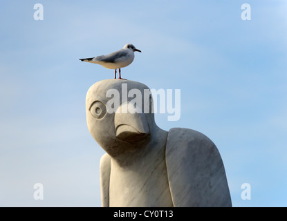 Seagull perching on 'Mythical South American Bird' sculpture. The Tern Project, The Stone Jetty, Morecambe, Lancashire, England. Stock Photo