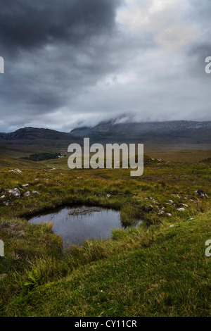 Highland moor and pool with incoming storm clouds over the Glensheildaig Forest, Wester Ross, Highlands, Scotland Stock Photo