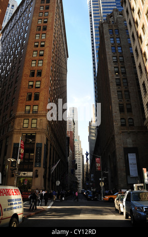 Blue sky sun shade urban alley portrait  buildings, cars, people, Wall Street at Pearl Street, towards Trinity Church, New York Stock Photo