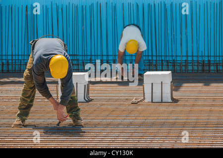Construction workers installing binding wires to steel bars Stock Photo