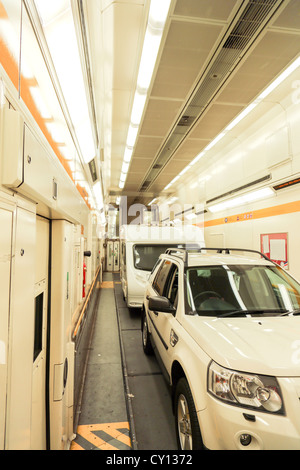 A car and trailer caravan inside a train carriage of a Eurotunnel Le Shuttle traveling through the Channel Tunnel. Stock Photo