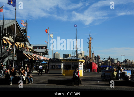 Blue sky view, to Brooklyn, flags, sail ship masts, water taxi ticket booth, people, Pier 17, South Street Seaport, New York Stock Photo