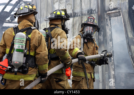 Firewoman and firefighters putting out a fire in an industrial building in Wisconsin Stock Photo
