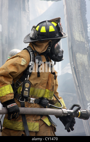 A woman firefighter holding a hoseline at a fire scene in Menomonee Falls Wisconsin Stock Photo