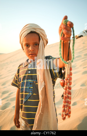 Tunisian boy is waiting for tourists in the Sahara desert, on a tourist point, so that he could sell some souvenirs. Stock Photo