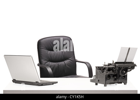 A laptop and an old fashioned typing machine on a table in modern office isolated on white Stock Photo